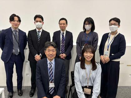 事務職の職員と職場の職員たちとの集合写真